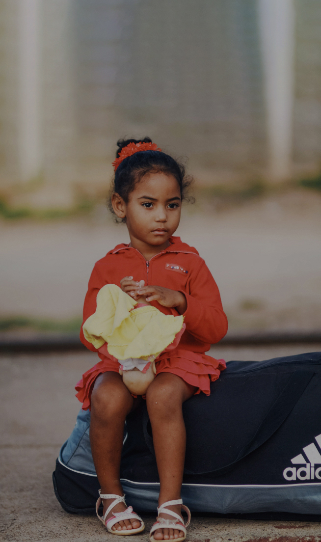 little girl sitting on backpack