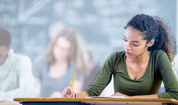 girl writing while sitting on desk